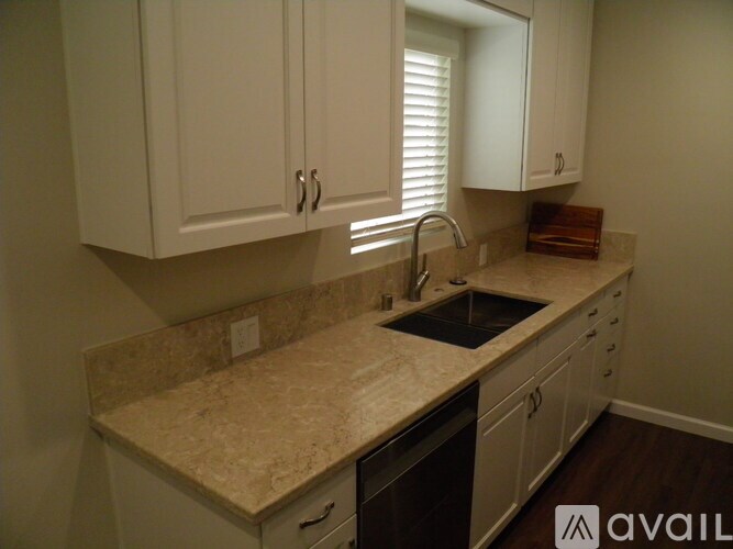 A kitchen with white cabinets and a granite countertop.