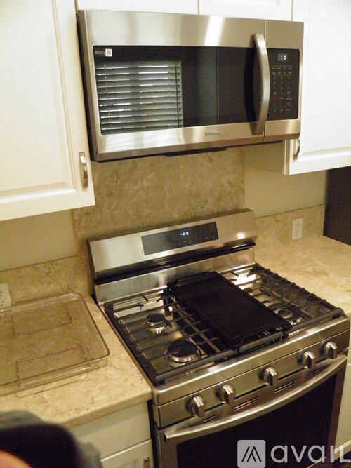 A stainless steel oven with a black stove top sits under a microwave.