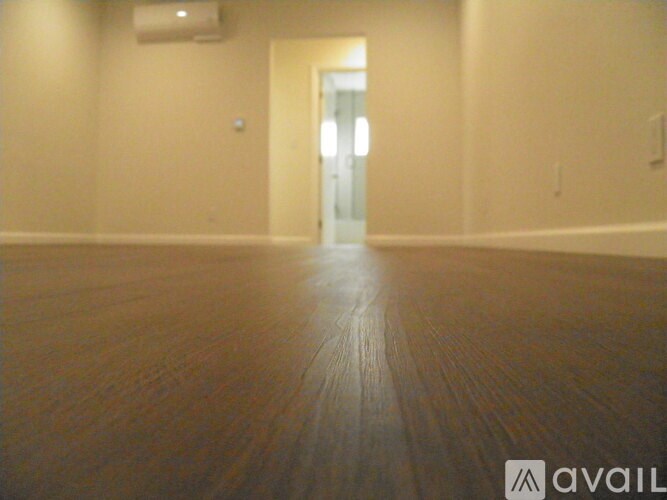 A room with a wooden floor and a doorway leading to another room.