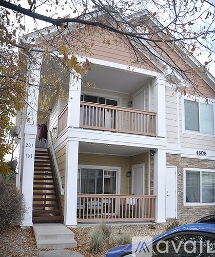 A two-story house with a balcony and a car parked in front.