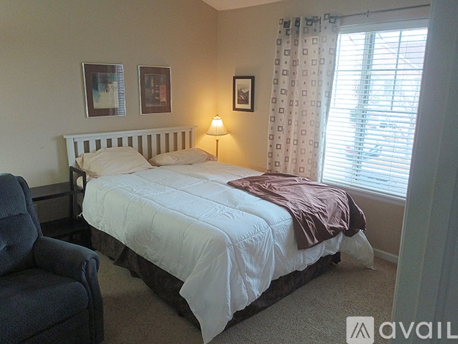 A bedroom with a bed, chair, and window.