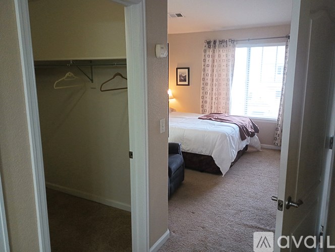 A bedroom with a bed, a window with curtains, and a picture on the wall.