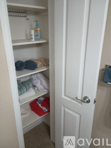 A white closet with a towel and a bottle on the shelf.