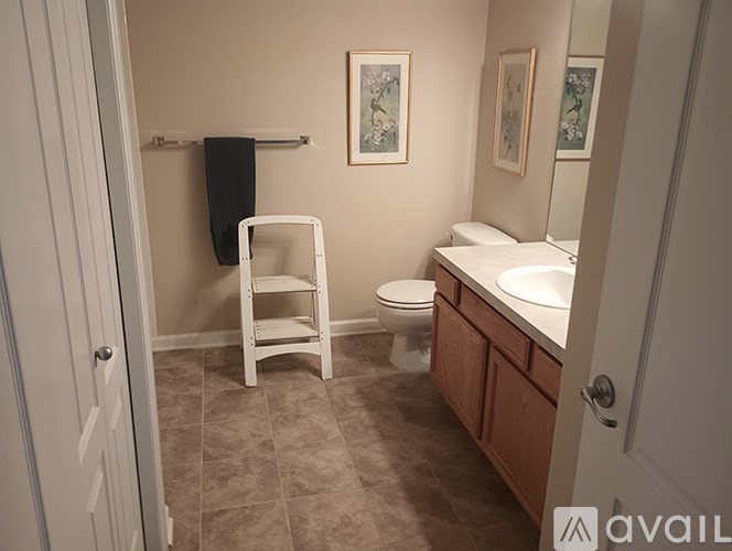 A bathroom with a toilet, sink, and chair.
