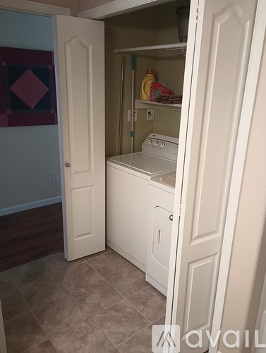 A white door is open to reveal a small kitchen with a washer and dryer.