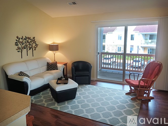 A living room with a white couch, a black chair, and a red chair.