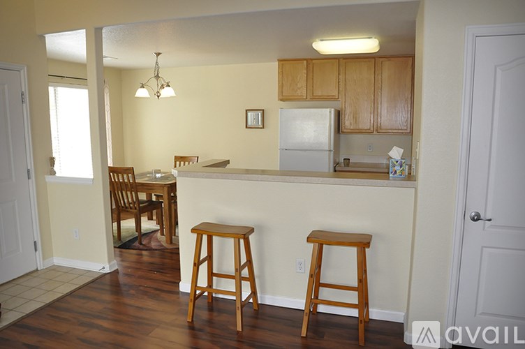 A kitchen with a white fridge and wooden bar stools.