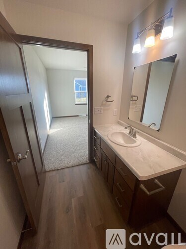 A bathroom with a sink, mirror, and a door leading to a hallway.