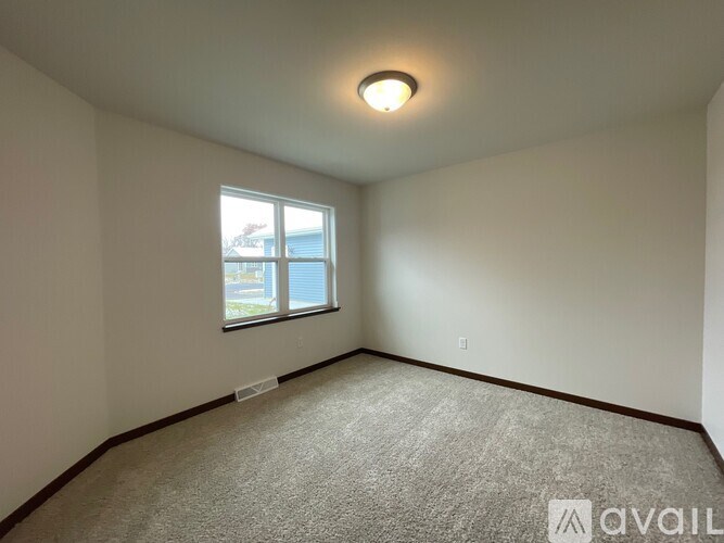 A carpeted room with a window and a light on the ceiling.