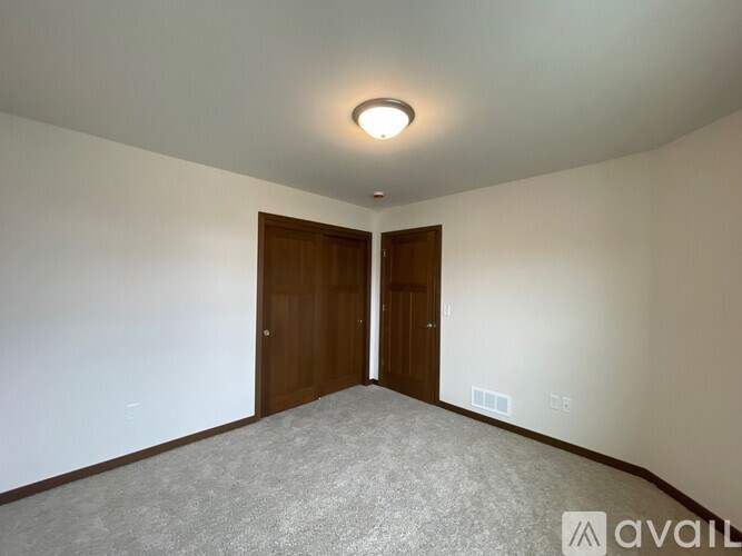 A room with a carpeted floor and two doors.
