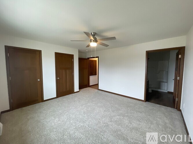 A room with a ceiling fan and carpeted floor.