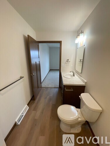 A bathroom with a toilet, sink, and mirror.