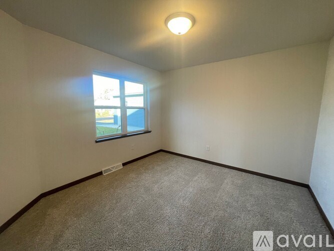 A room with a carpeted floor and a window letting in natural light.