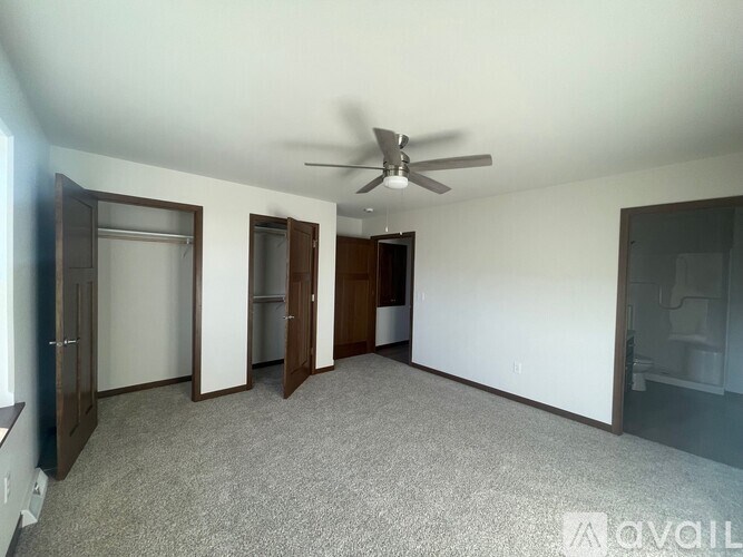 A room with a ceiling fan and carpeted floor.