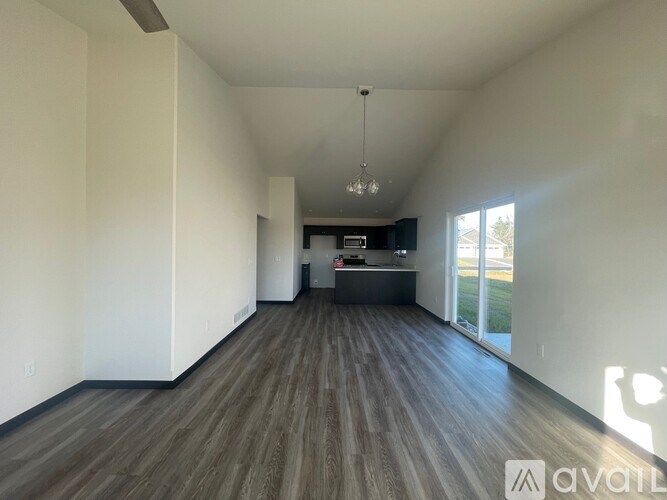 A spacious room with wooden flooring and a chandelier hanging from the ceiling.