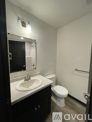 A bathroom with a sink, toilet and mirror.