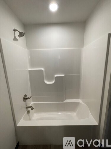 A white bathtub with a shower head and faucet.