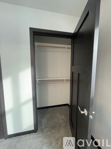 A black door with a glass window is open to a carpeted hallway.