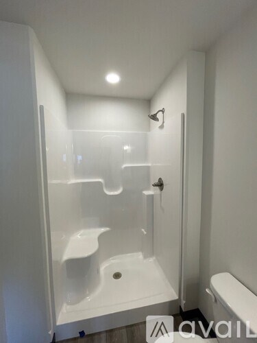 A white bathroom with a glass shower stall and toilet.