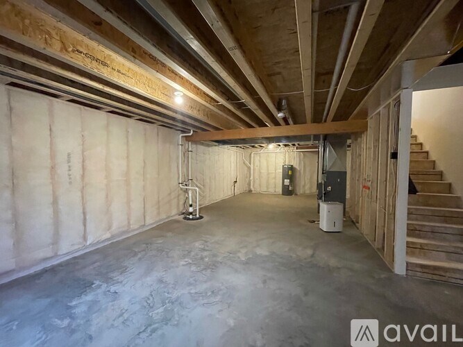 A room under construction with exposed ceiling beams and unfinished walls.