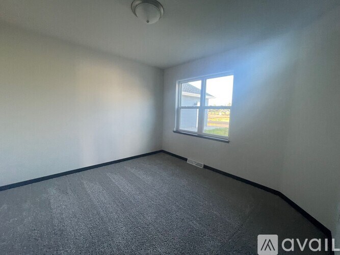 A room with a grey carpet and a window.
