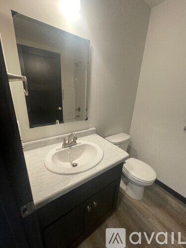 A bathroom with a sink, toilet and mirror.