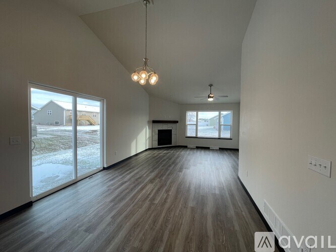 A room with a ceiling fan and a window with a view of a fence and a house.