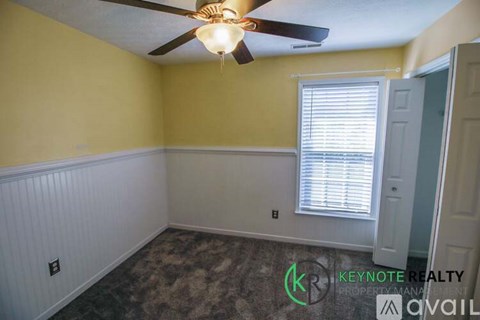 A room with a ceiling fan and a window with blinds.