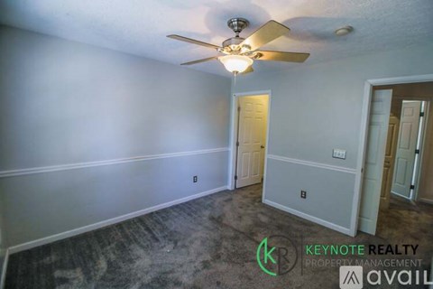 A room with a ceiling fan and a door.