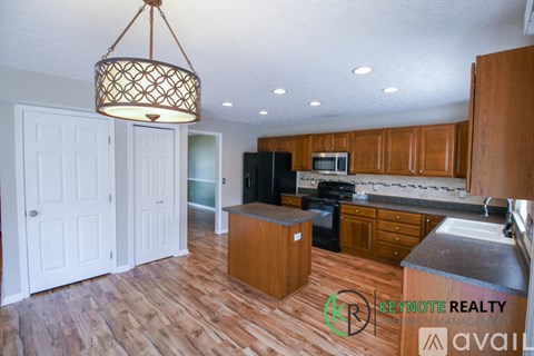 A kitchen with wooden floors and a hanging light fixture.