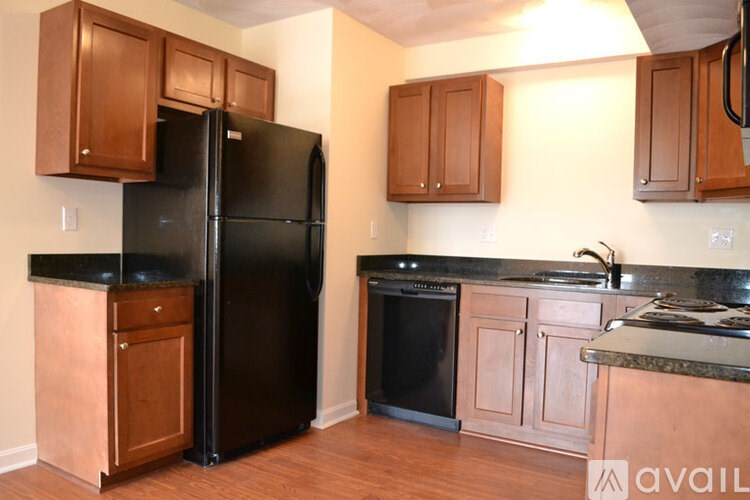 A kitchen with a black refrigerator and wooden cabinets.