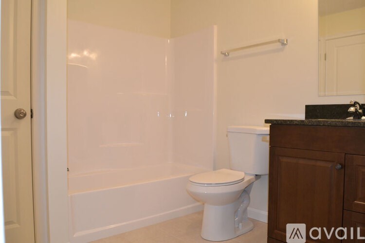 A white toilet sits in a bathroom with a walk-in shower.