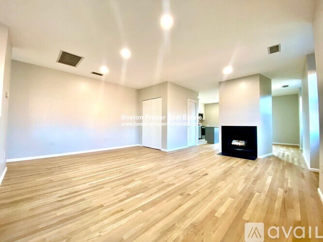 A spacious room with wooden flooring and a black fireplace.
