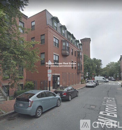 A street view of a residential area with cars parked on the side of the road.