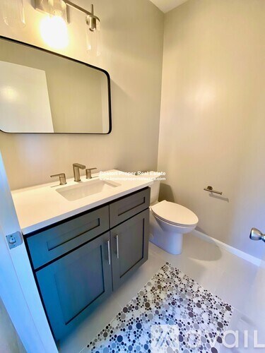 A bathroom with a sink, toilet, and a mirror.