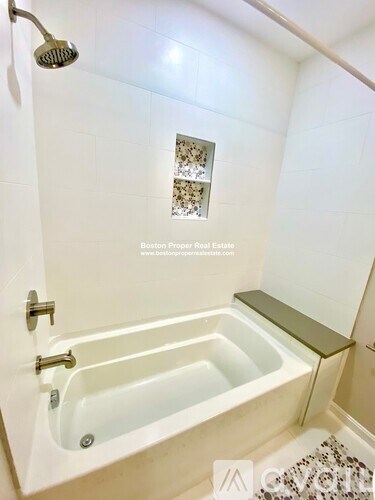 A white bathroom with a tub and a shower head.