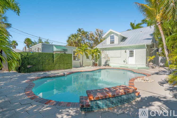 A pool surrounded by a brick border in a backyard.