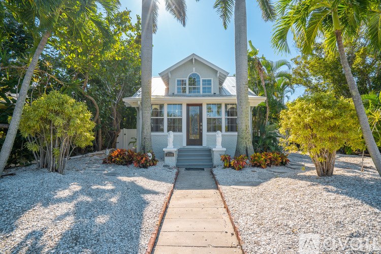 A house with a white front yard and a gravel path leading to the front door.