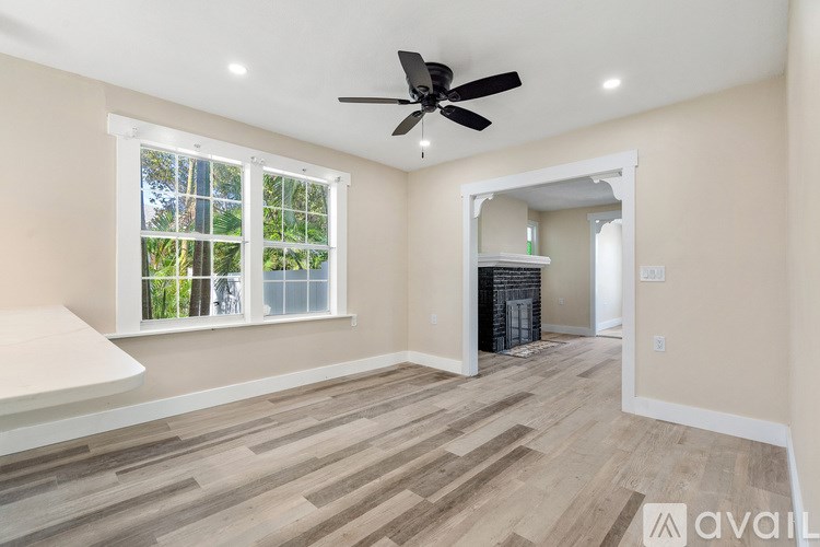 A room with a ceiling fan and a window with a view of trees.