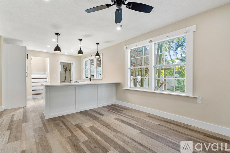 A room with a ceiling fan and a window with a view of trees.
