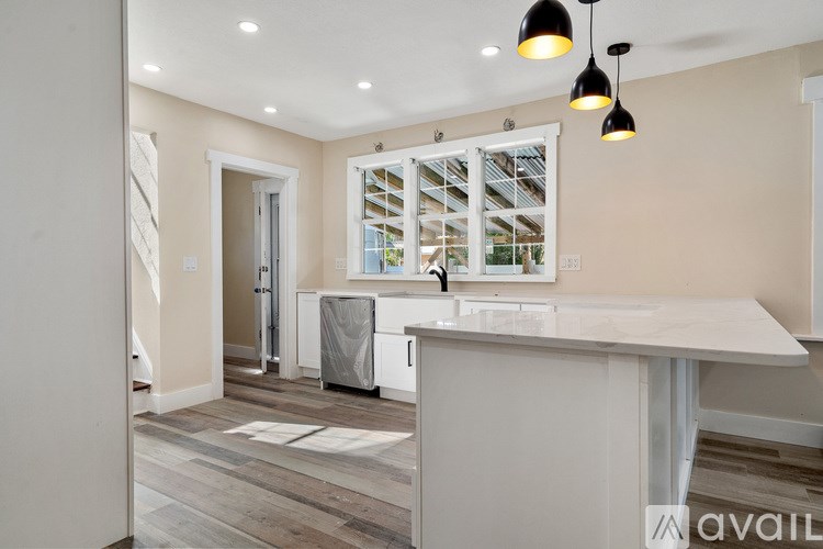 A kitchen with a white countertop and a window with blinds.