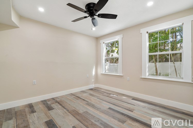 A room with a ceiling fan and wooden flooring.