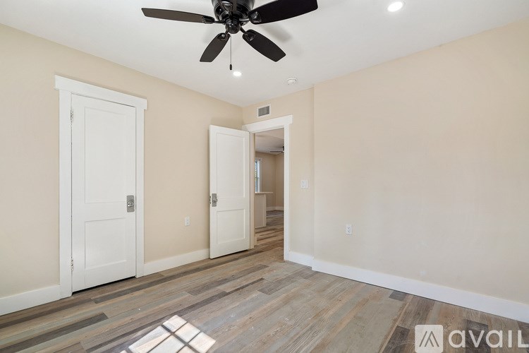 A room with a ceiling fan and wooden flooring.