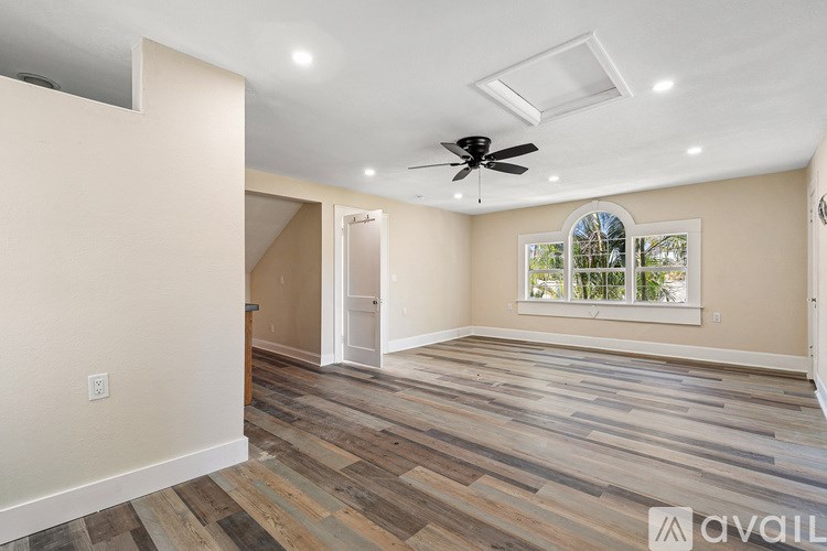 A spacious room with wooden flooring and a ceiling fan.