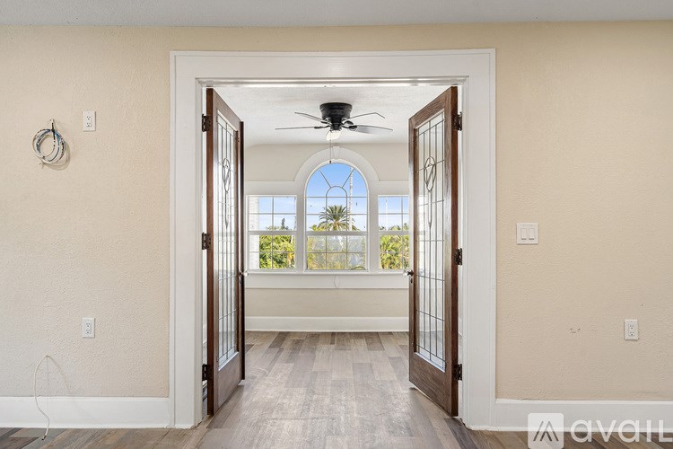 A room with a doorway leading to a balcony with a fan on the ceiling.