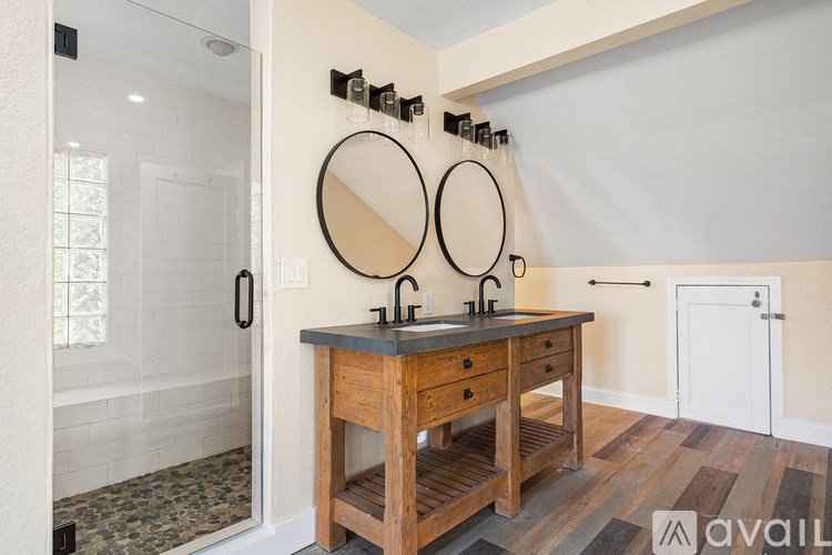 A bathroom with a wooden vanity and two round mirrors.