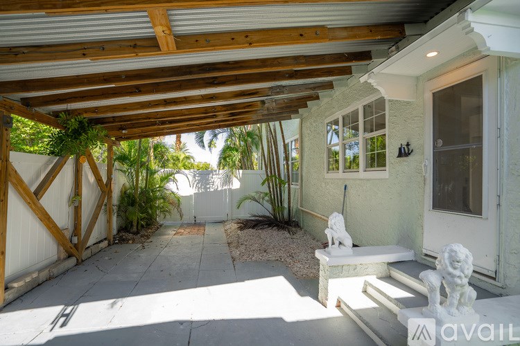 A white house with a wooden pergola over a patio.
