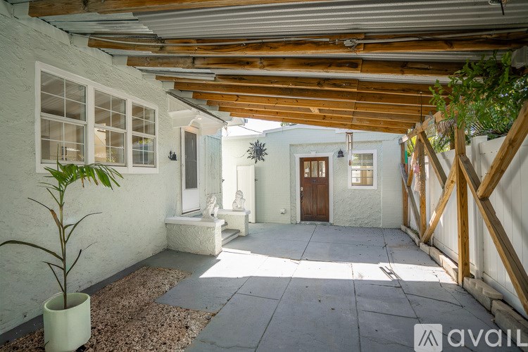 A white building with a wooden roof and a plant in a white pot.