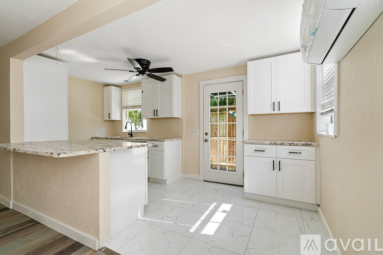 A kitchen with white cabinets and a marble countertop.