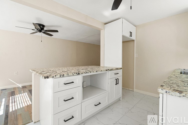 A kitchen with a marble countertop and white cabinets.